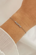Bracelet Mama argenté en acier inoxydable avec inscription cursive, porté au poignet