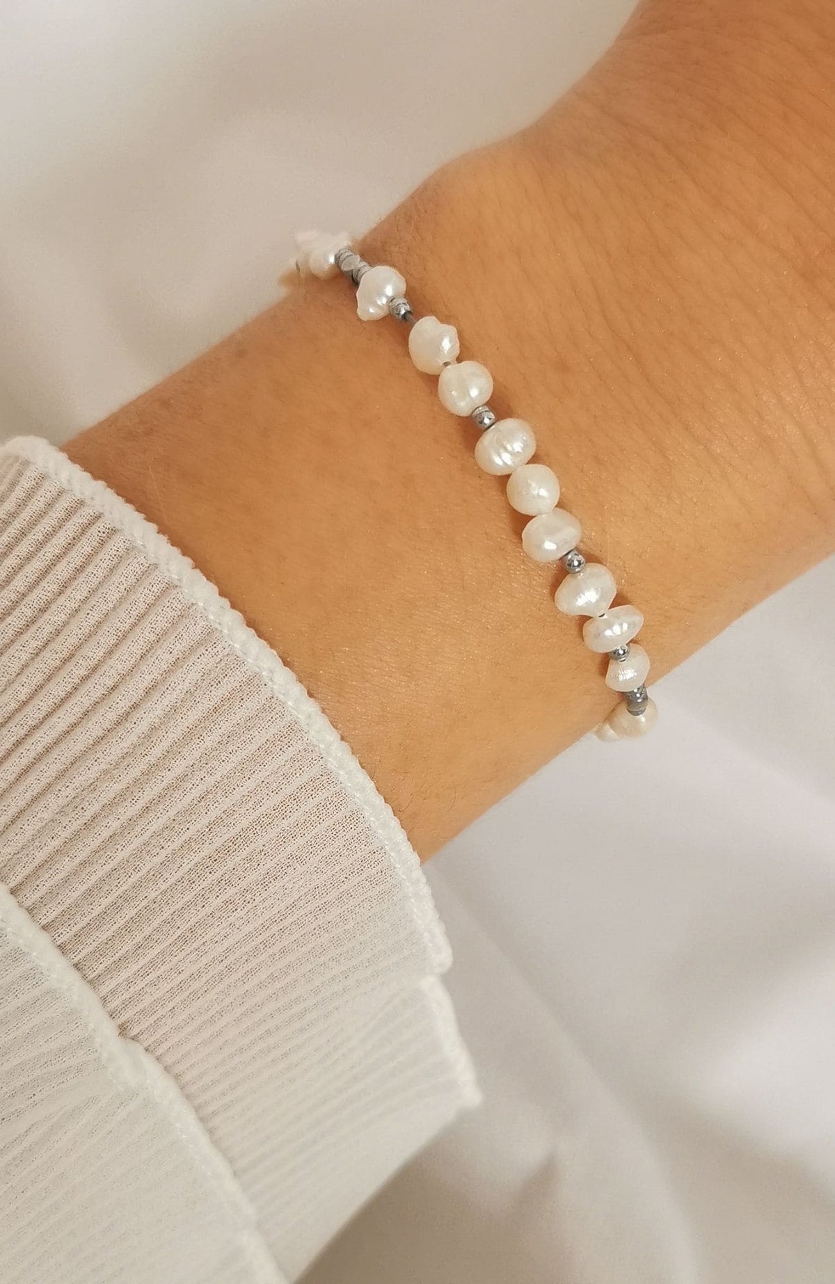 Bracelet Polynésie argenté avec perles d'eau douce sur chaîne en acier inoxydable, porté au poignet