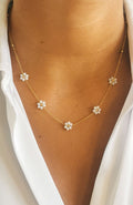 Collier fleurs blanches émaillées sur chaîne fine dorée en acier inoxydable, porté au cou