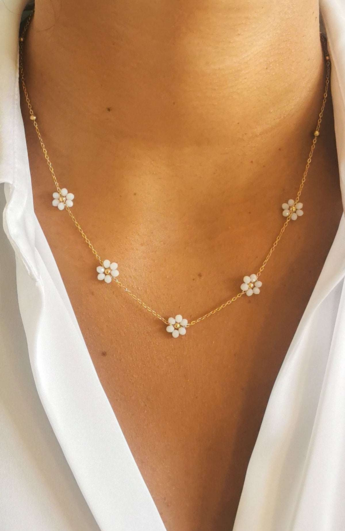 Collier fleurs blanches émaillées sur chaîne fine dorée en acier inoxydable, porté au cou