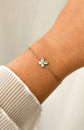 Bracelet Fly argenté avec fleur sertie de zircons en acier inoxydable, porté au poignet