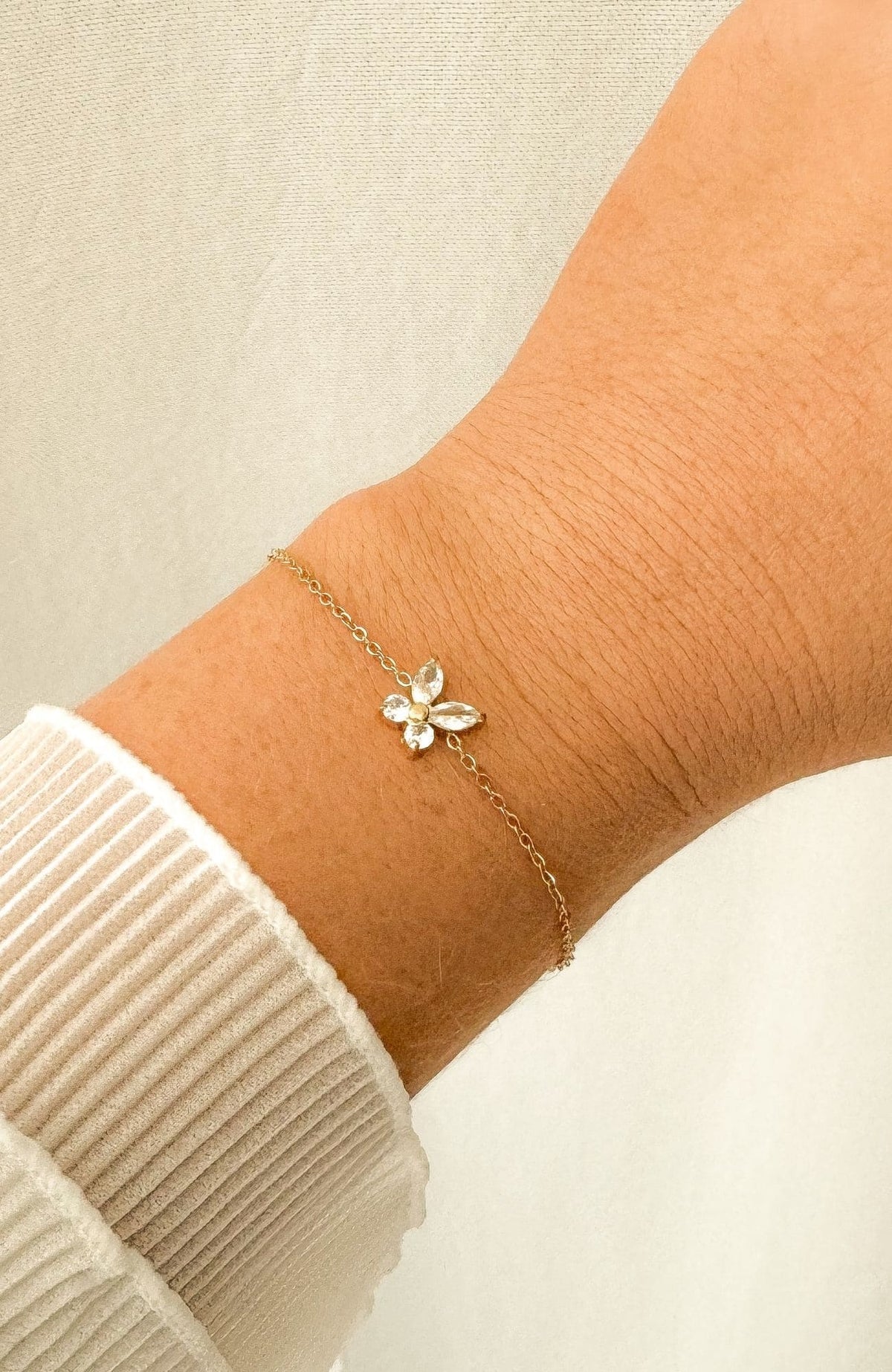 Bracelet Fly doré avec fleur sertie de zircons en acier inoxydable, porté au poignet