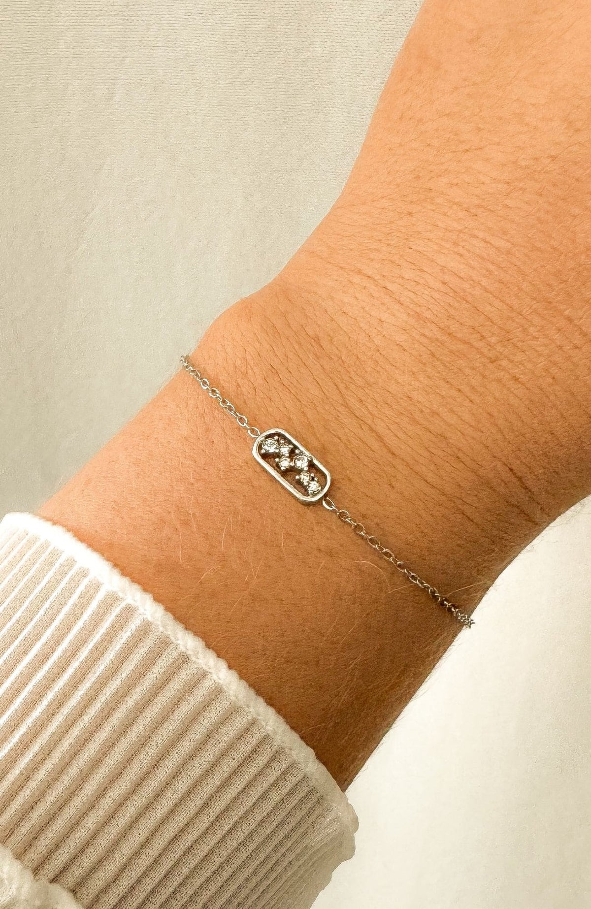 Bracelet Héloïse argenté avec pendentif constellation serti de zircons, porté au poignet