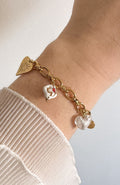 Bracelet Bianca avec charms nacre et émail blanc en acier inoxydable doré, porté au poignet