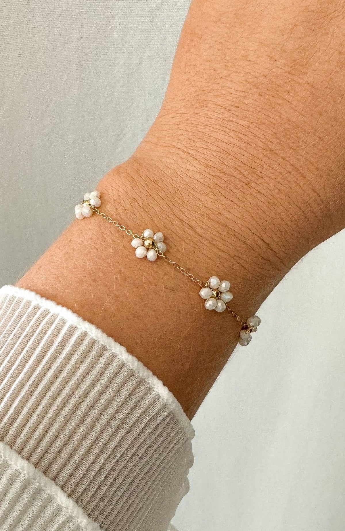 Bracelet Florida doré chaîne fine avec pampilles fleurs en perles, porté au poignet