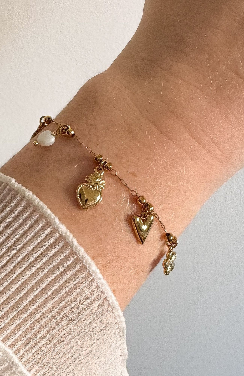 Bracelet Jodie doré avec charms cœurs et perle, porté au poignet